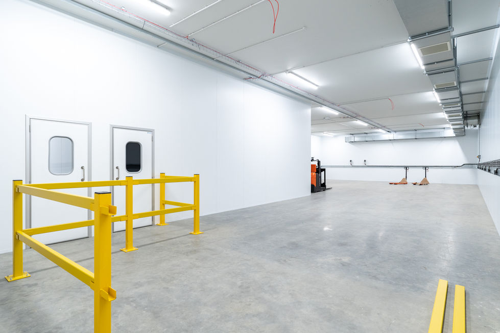 Large fire rated temperature-controlled warehouse fork truck charging room with yellow safety barriers and insulated doors
