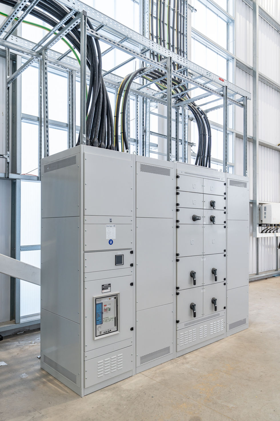 Grey electrical distribution cabinet installed within warehouse structure