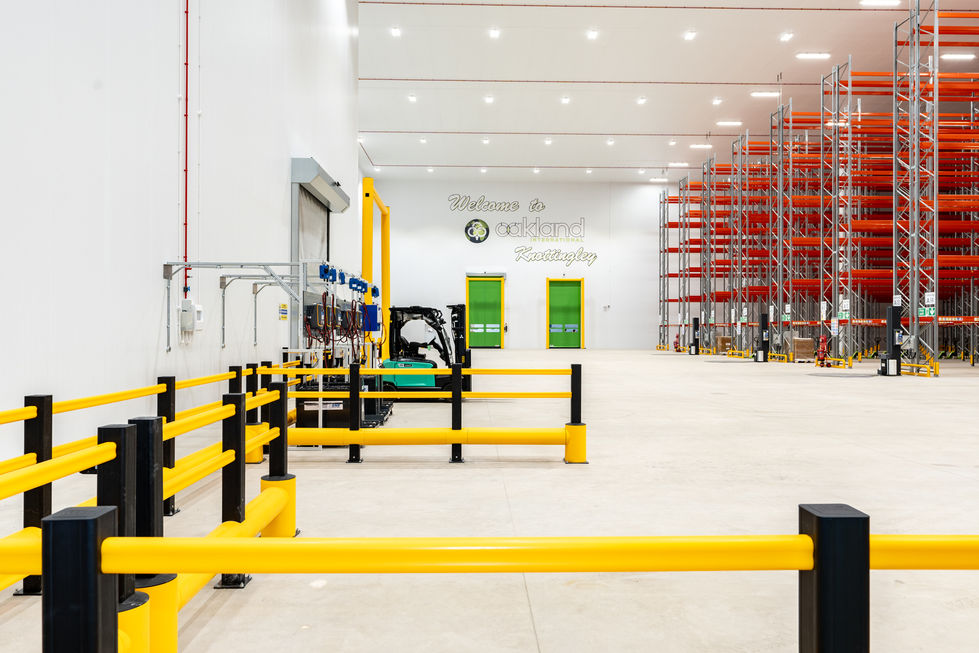 Warehouse interior with yellow safety barriers, forklift area and high bay racking