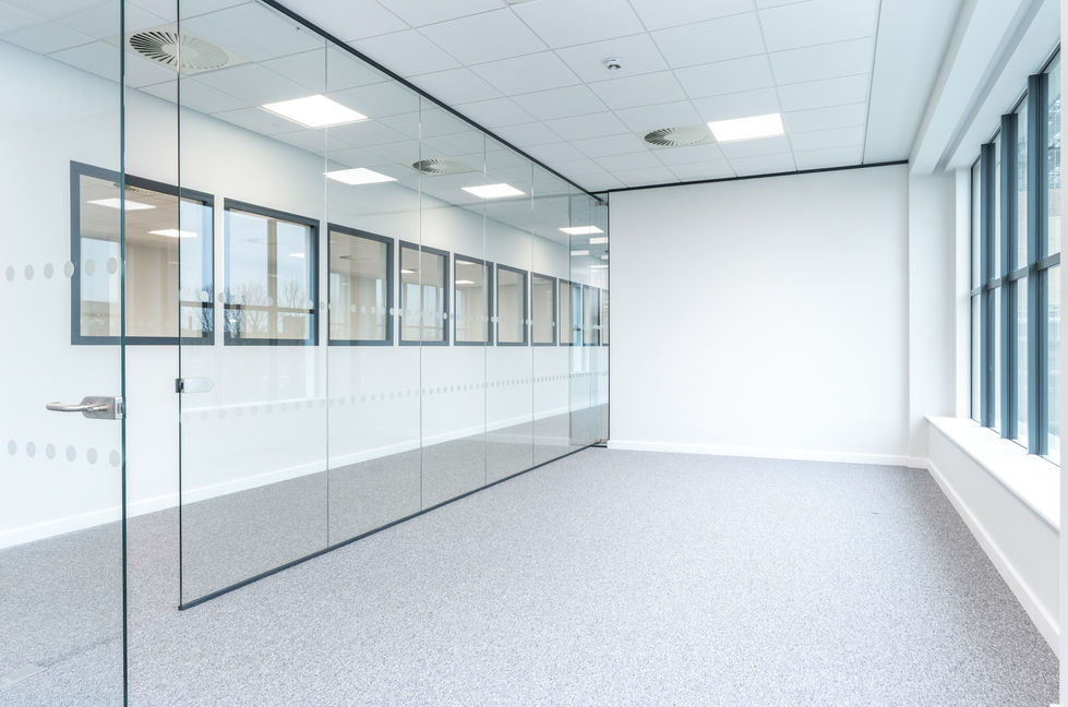 Glass-partitioned office room with carpet flooring and full-height external windows
