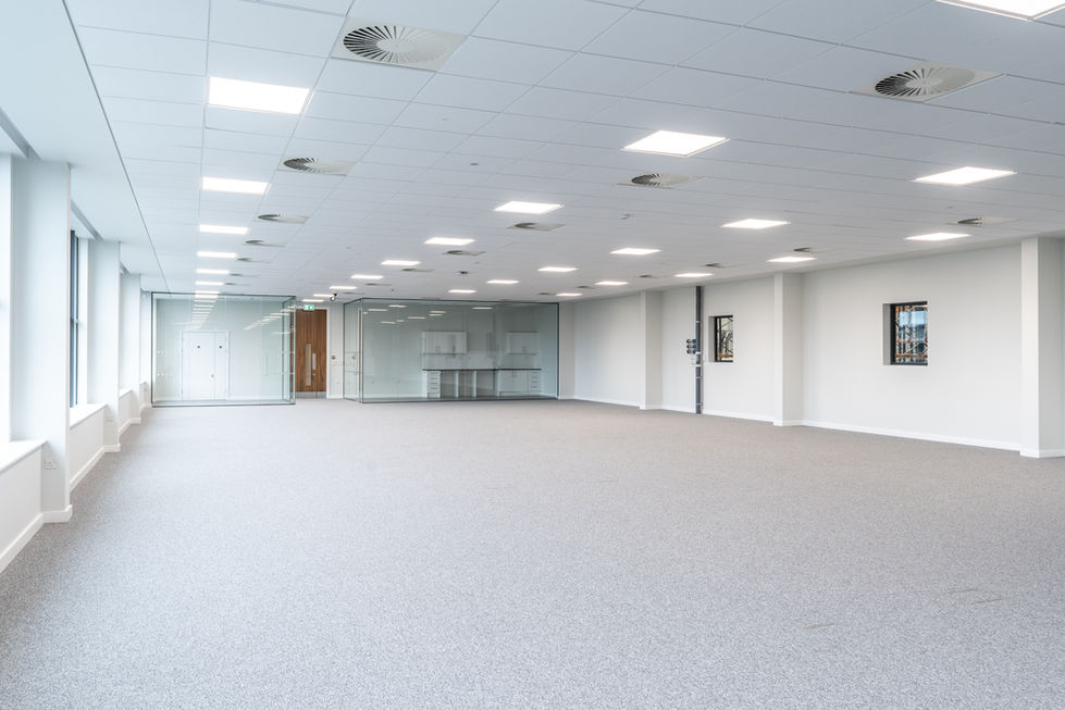 Open-plan office floor with glass meeting room, kitchenette and full-height external windows