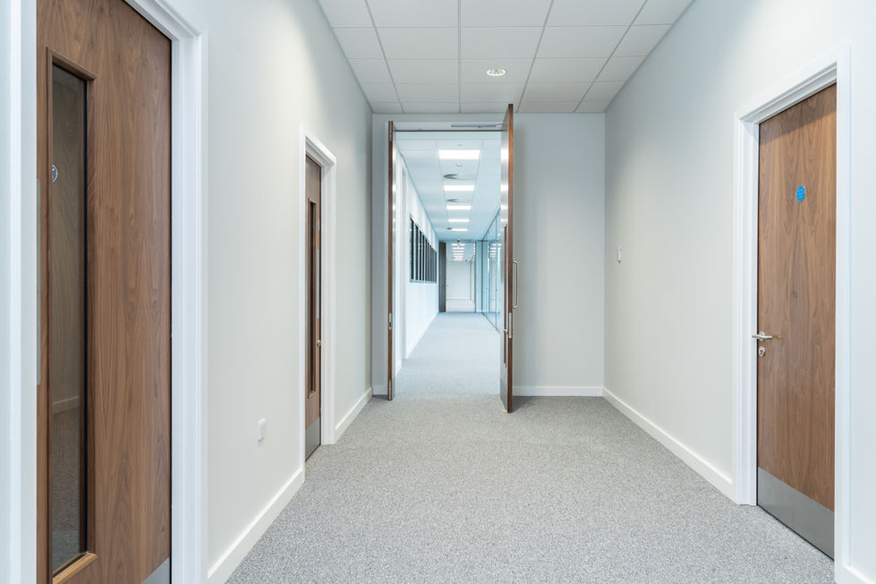 Office corridor with timber doors, carpet flooring and glazed partitions beyond