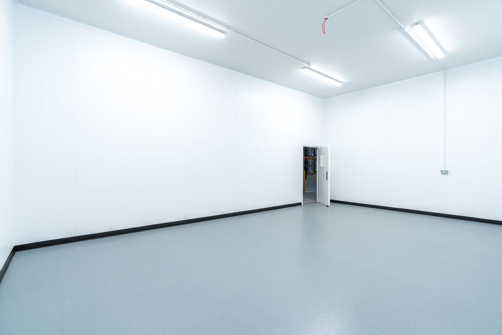 Empty hygienic changing / locker room with white insulated wall panels and resin floor finish