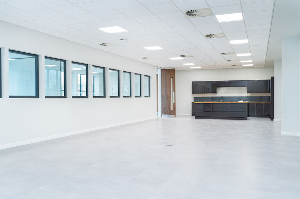 Open-plan staff breakout area with integrated kitchen, grey flooring and internal glazing