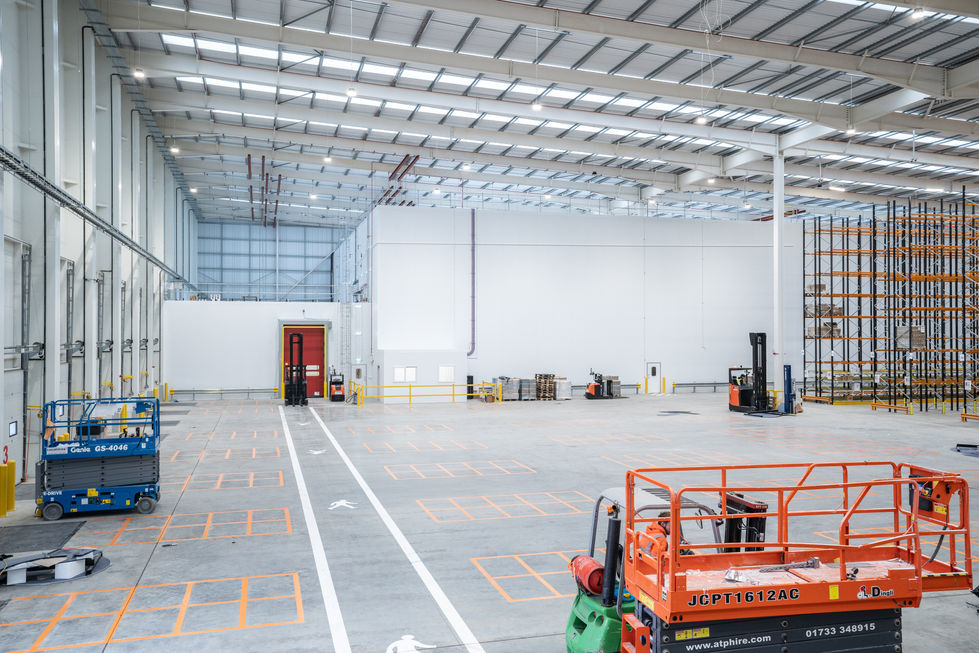 Wide internal warehouse view during fit-out with cold store pod, access platforms and marked floor zones at the Kikkoman project