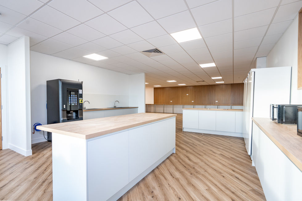 Staff kitchen and breakout area with island unit, vending machine and timber wall panelling