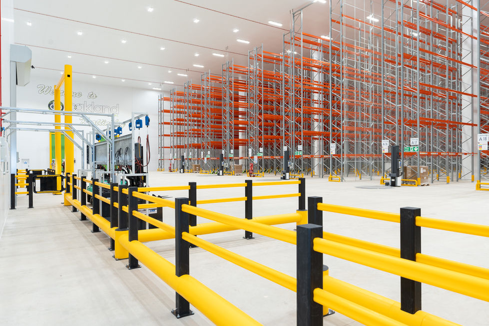 Wide internal view of warehouse with safety barriers and pallet racking
