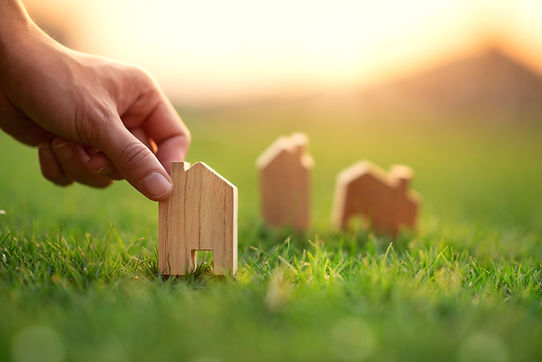 Hand of woman choosing mini wood house model on green grass, Planning buy Real Estate, eco