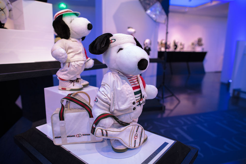 two dog statues wearing white tennis gear, holding tennis racket bags