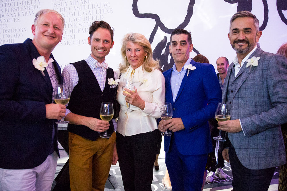 four men and a woman posing with wine glasses in their hands