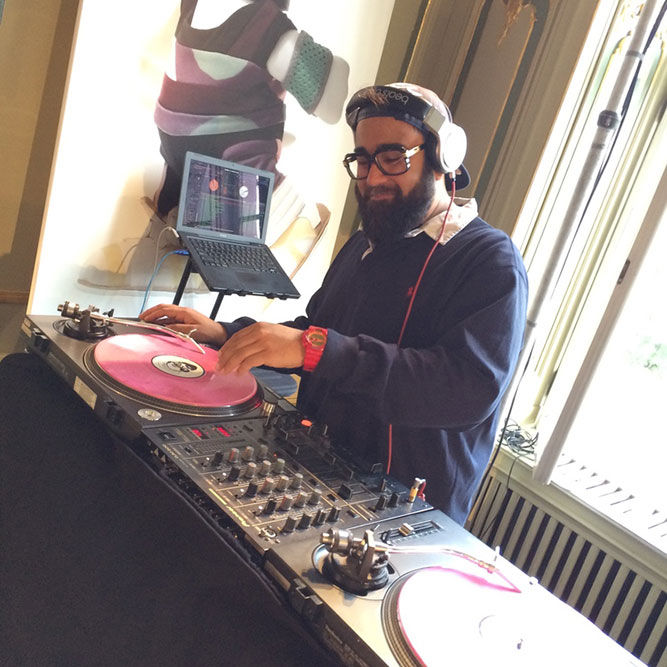 a bearded man wearing headphones working a dj deck