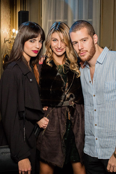 two women and a man pose in front of a window