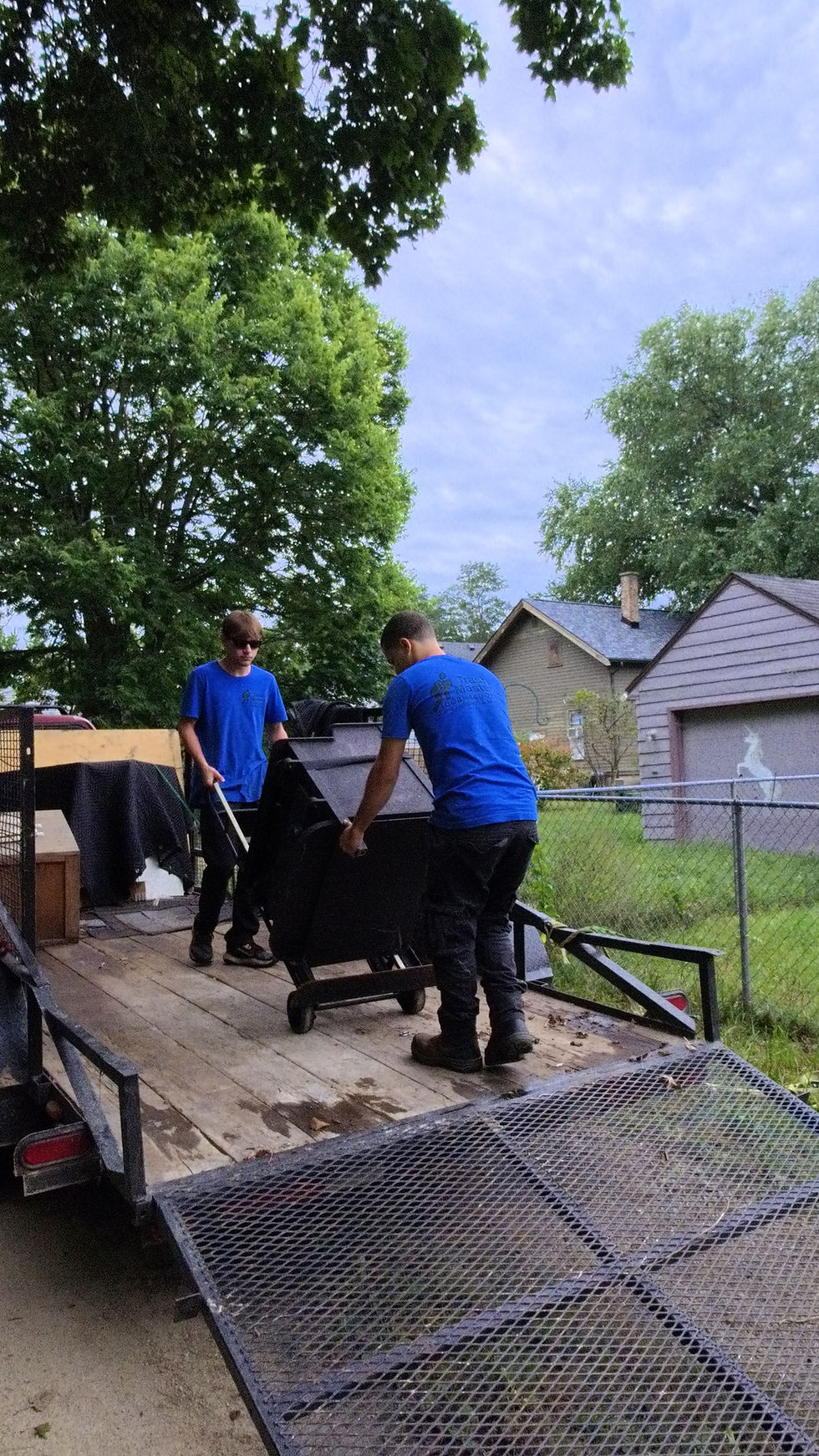 Two men performing junk removal Janesville on a trailer.