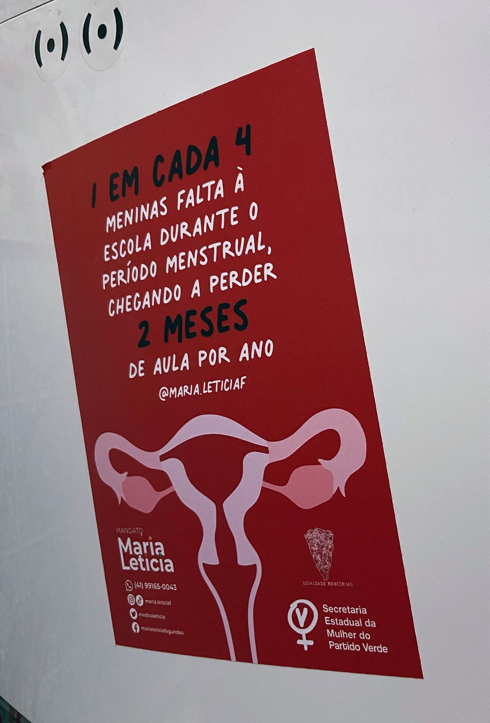 Adesivo vermelho com a frase "1 em cada 4 meninas falta a escola quando está menstruada" e o desenho de um útero