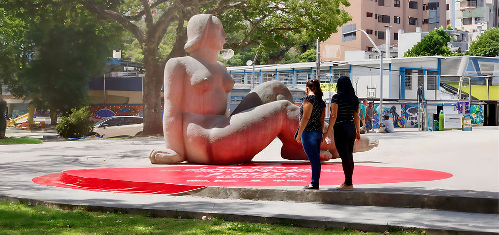 Estátua da mulher nua com o adesivo vermelho redonto ao chão e duas mulheres observando a intervenção urbana