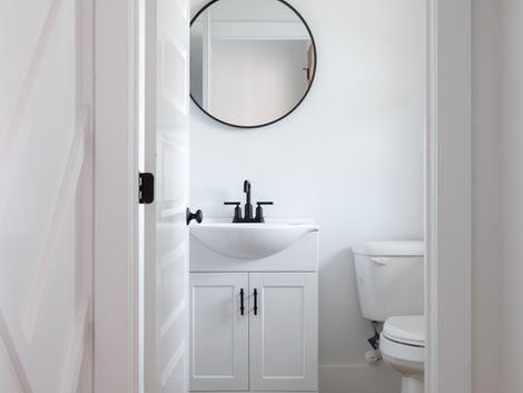 Half bathroom with black and white design and white oak flooring in golf community in coastal North Carolina.