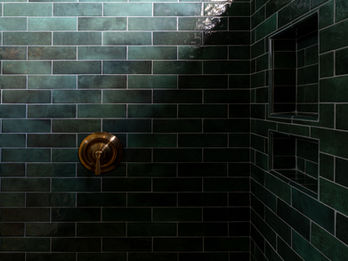 Alternate angle of the shower with dark green tile, highlighting the tile and brasss shower fixtures, adding a touch of elegance to this Cape Carteret custom home. 