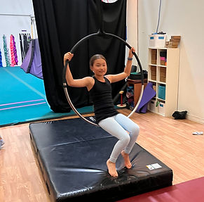 Youth aerial student sits in a lyra at Denver Circus Collective.