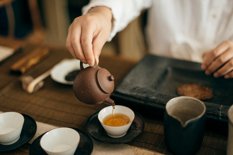 a person pouring tea into a small white cup
