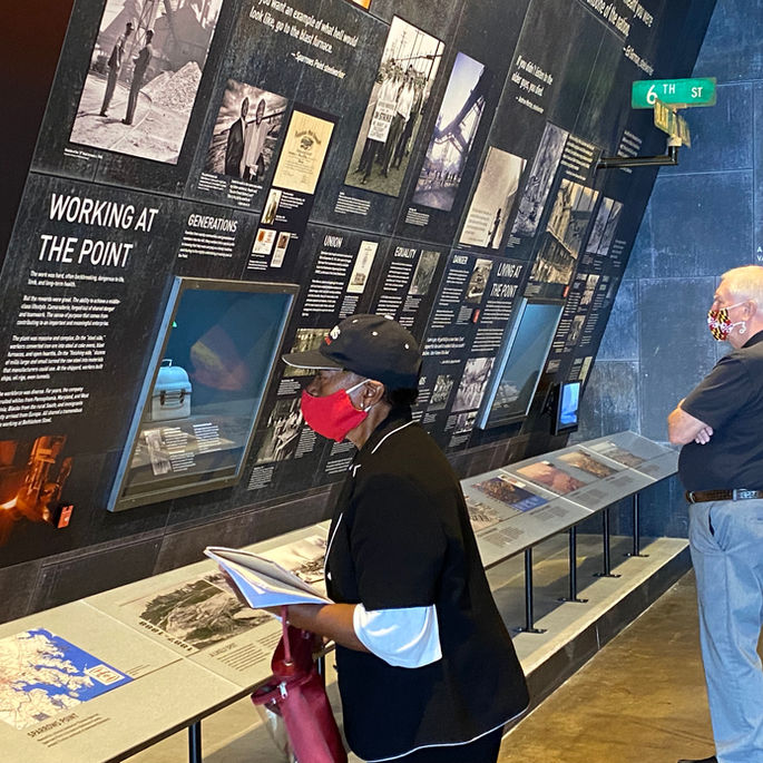Fire and Shadow exhibition with woman and a man reading exhibition text.