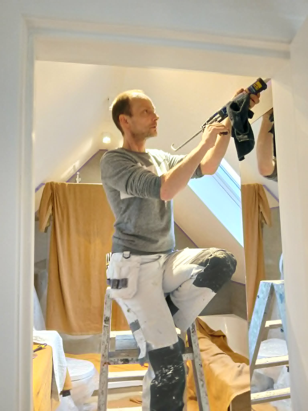 Portretfoto van een klusser op een ladder in een badkamer
