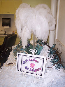 Spa party welcome table with ostrich feather centerpiece and floral pieces.