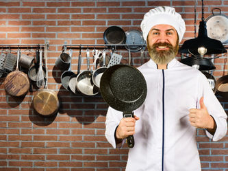 chef holding a nonstick pan with lots of sticky pans in the background, representing nonstick coatings