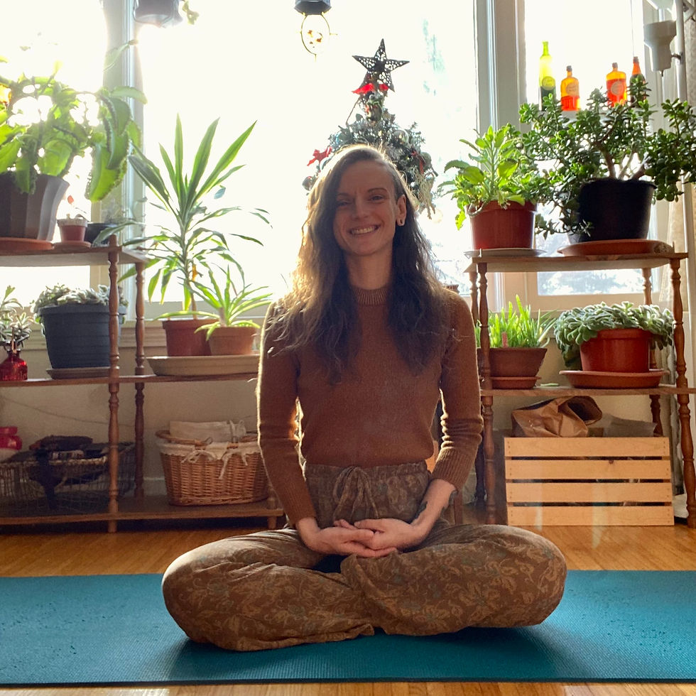 Me sitting in easy pose on a yoga mat, surrounded by plants in my home studio, grounded and centered.