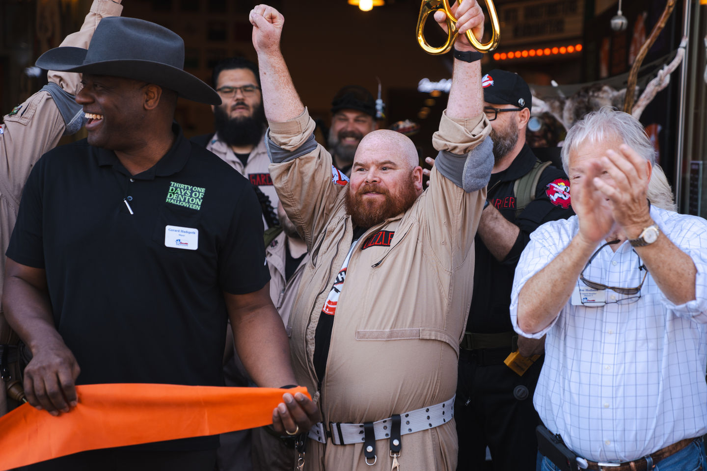A man dressed as a Ghostbuster with his harms razed and holding ceremonial sizers.
