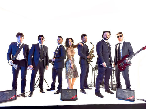 The Bix Co. live band standing on stage posing with their instruments and speakers