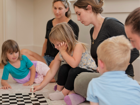 Children sitting with parents playing chess