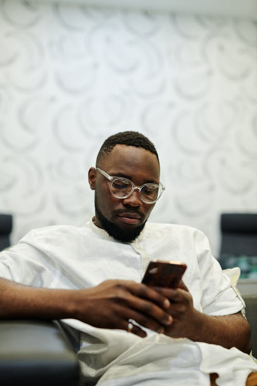 A man wearing a white shirt using his mobile phone.