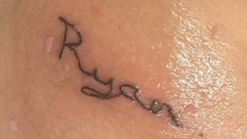 Vista de cerca de un tatuaje descolorido y borroso en el antebrazo.