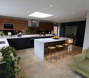 Handleless kitchen with exotic wood wall units and a white island under a roof light, Northcote Crescent, West Horsley