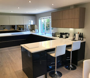 Gloss blue handleless kitchen with white bar stools and wood-effect wall units, Danesfield, Ripley
