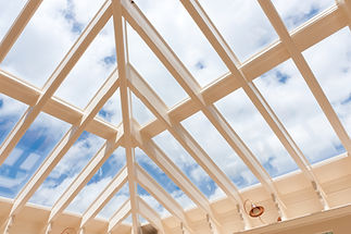 A beautiful and light conservatory roof from the inside, with lots of white beams trying to reveal a bright blue sky.