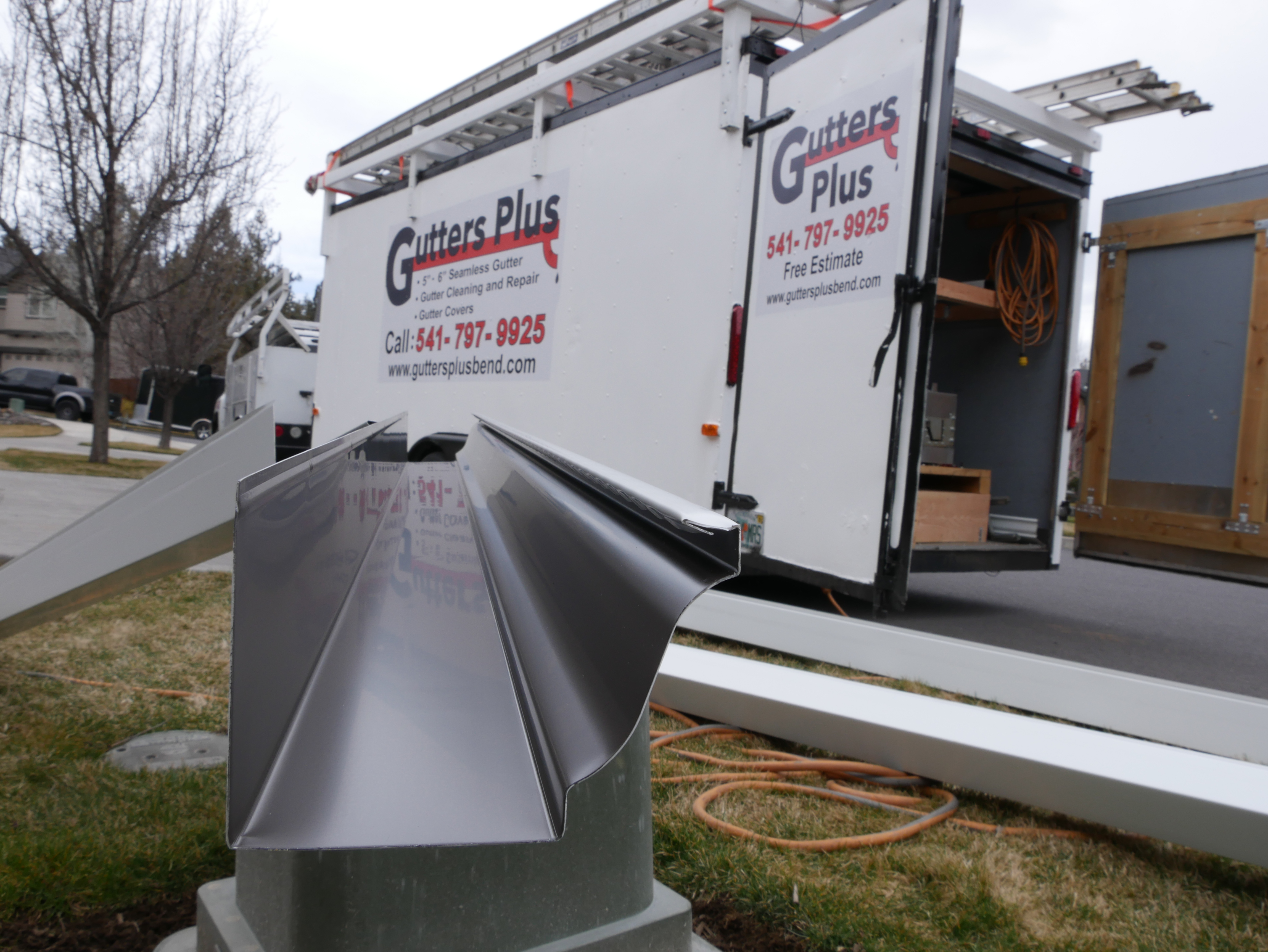 Seamless gutter stock and Gutters Plus trailer set up at a Central Oregon job site