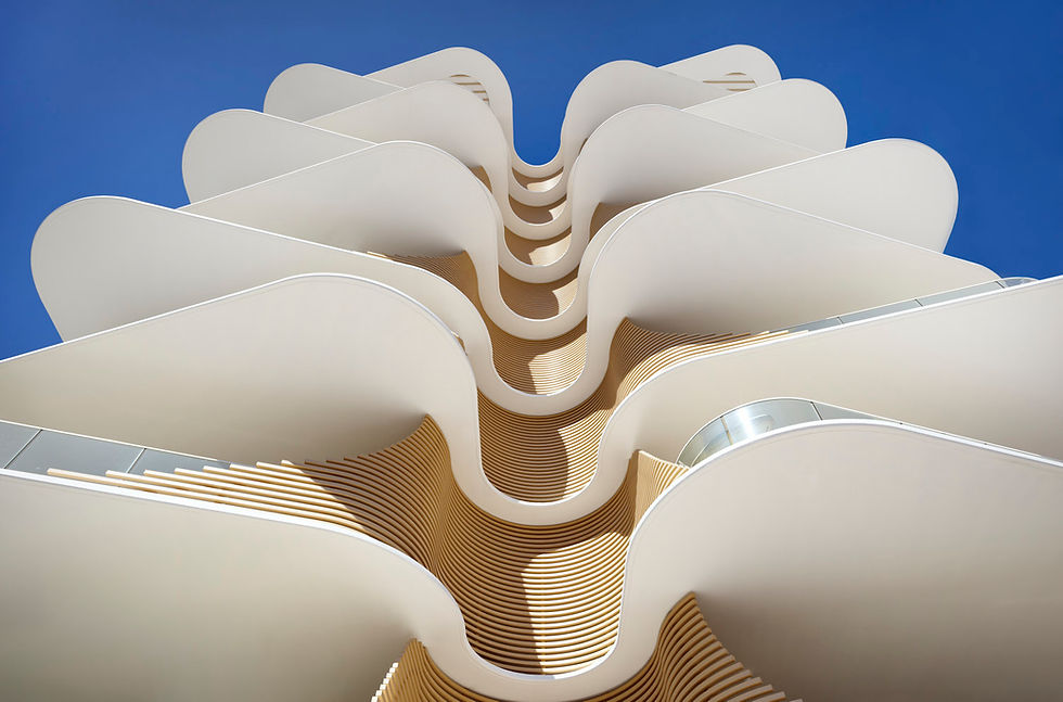Modern white undulating balconies against a clear blue sky.