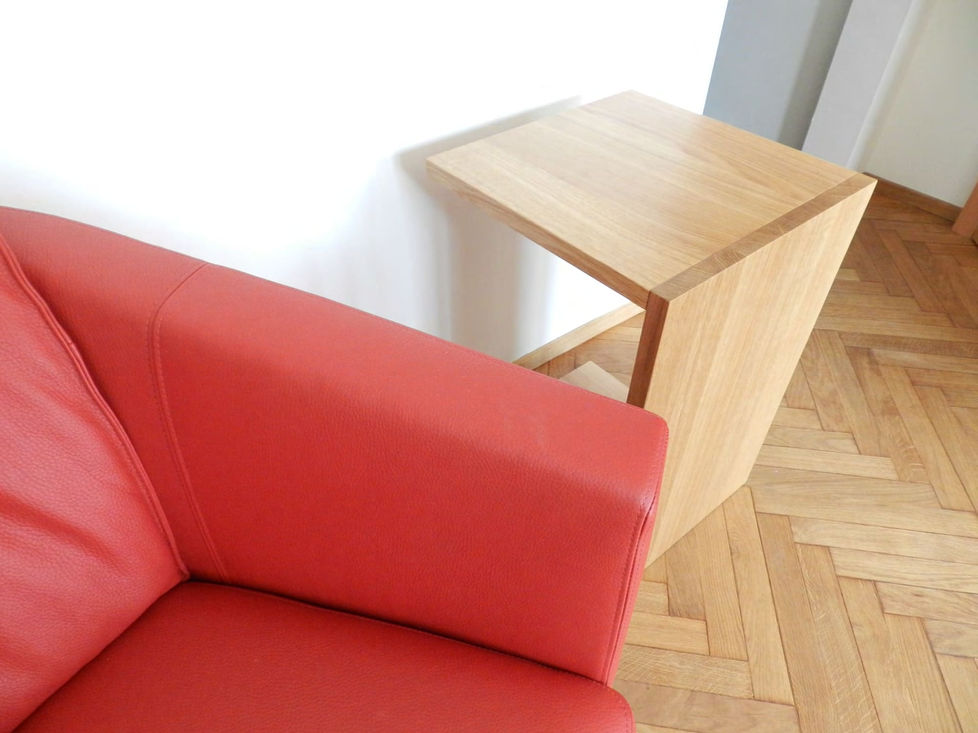 Rotes Ledersofa neben einem C-förmigen Holztisch