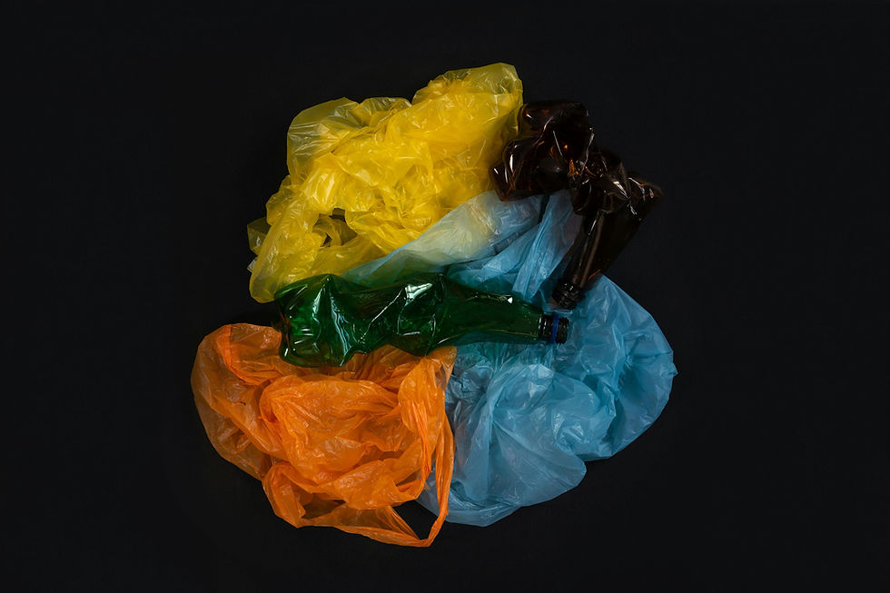 Different coloured plastic bags and bottless against a black background