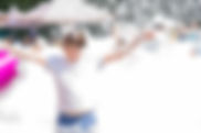happy little boy with foam on his head, in wet clothes at a foam party or holiday on a sun