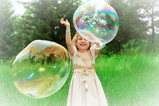 Pretty%20little%20girl%20is%20playing%20with%20big%20bubbles%20in%20a%20park._edited.jpg