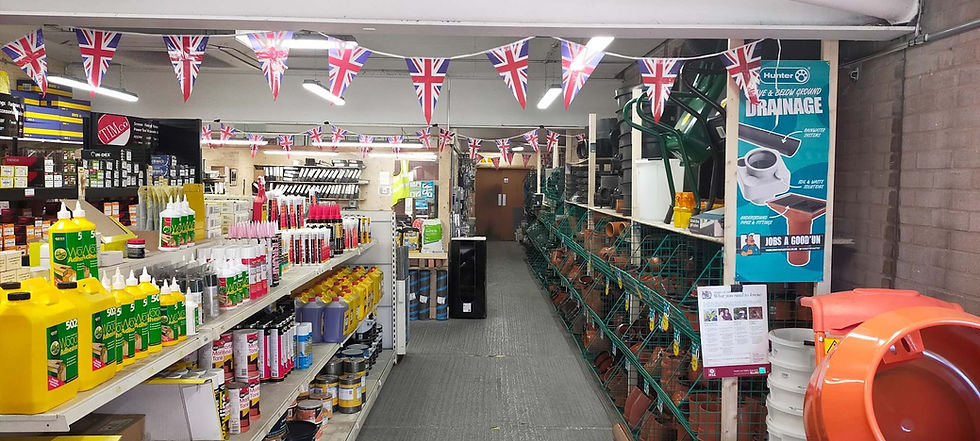 A hardware store aisle filled with paint, adhesives, and garden supplies, decorated with Union Jack bunting