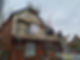 A house with scaffolding on the roof and a ladder leaning against the side