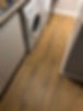 A laundry room floor features light wood laminate with visible grains