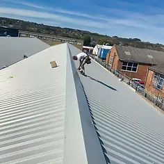 A worker balances on a corrugated metal roof