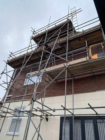 Angle shot of scaffolding covering the upper floors and roof area of a house