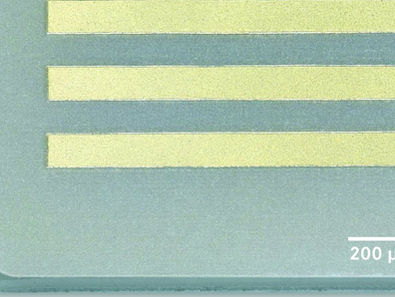 High-magnification image displaying three parallel gold-plated circuit paths on ceramic