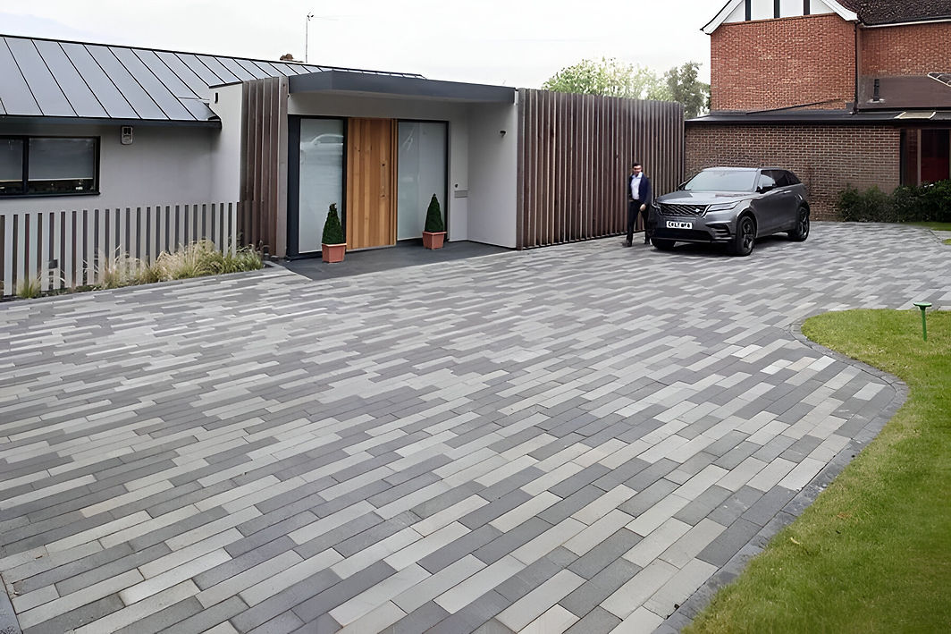 A modern house with a sleek driveway featuring grey and white interlocking pavers