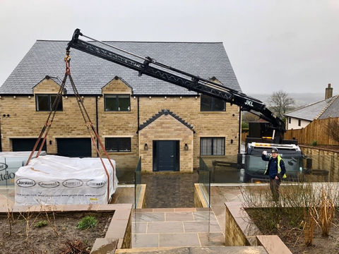 A crane lifting a white sheet over a house